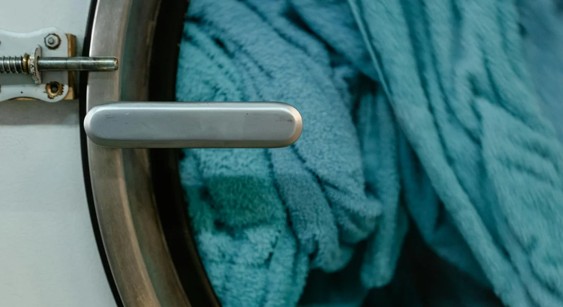 Close-up of a washing machine door with a blue towel inside