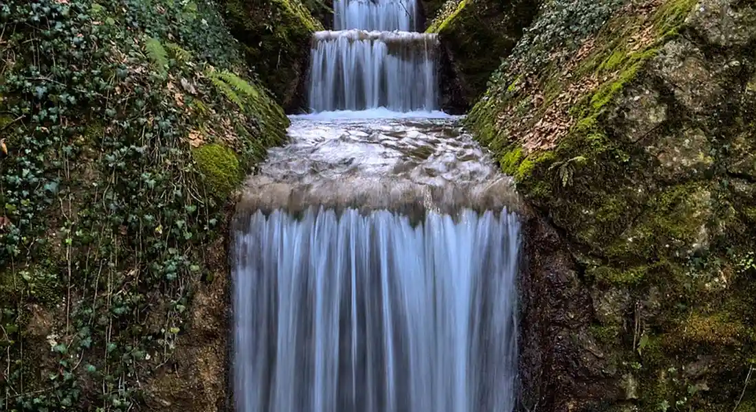 Water cascading over mossy rocks, illustrating the flow and control head concept of a water softener.