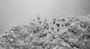 Close-up of coarse water softener salt crystals scattered on a surface