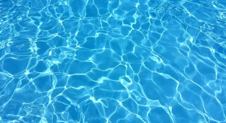 Close-up of clear blue water with sunlight reflections on the surface.