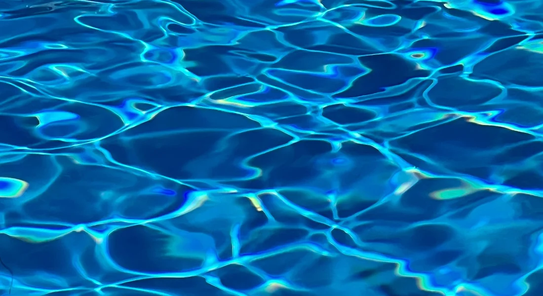 Close-up image of a blue water surface with light reflections, illustrating water hardness testing for a home water softener.