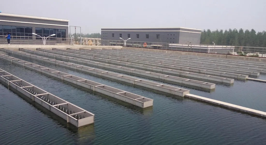 Industrial water treatment facility with multiple rectangular basins and a building in the background