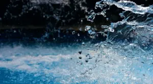 Close-up of blue water in motion with a splash and bubbles, illustrating a water treatment process