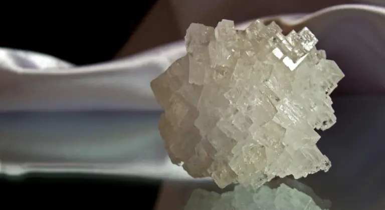 Close-up of large translucent salt crystals being held by a gloved hand