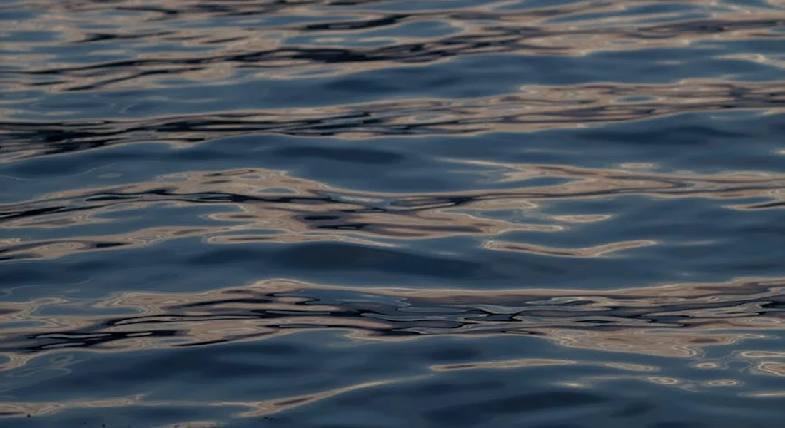 Close-up of blue water surface with gentle ripples and reflections