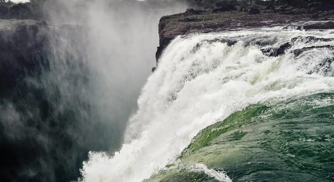 A dramatic waterfall cascading over a cliff edge with mist.