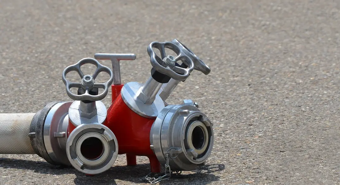 Red check valve with wheel-handled fittings lying on a rough concrete surface