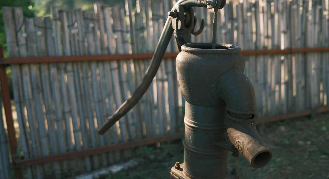 Close-up of a vertical well pump with electrical wiring and piping outdoors