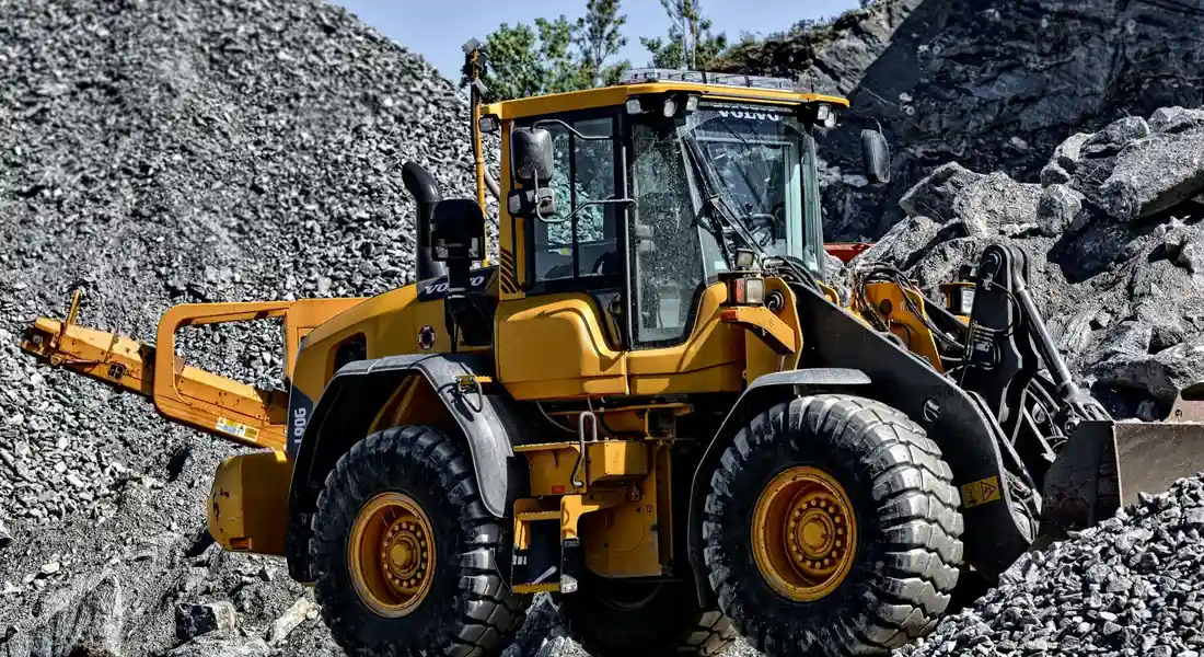 Yellow wheel loader on a rocky construction site, preparing to dig a sump pit.
