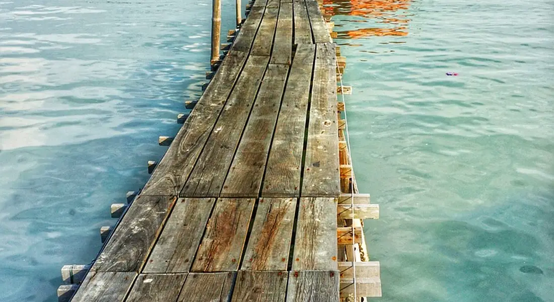Weathered wooden dock extending into turquoise water; no sump pump visible.