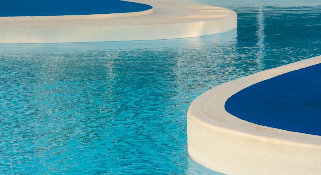 Close-up of a bright blue swimming pool with curved white edges, symbolizing spring inspection.